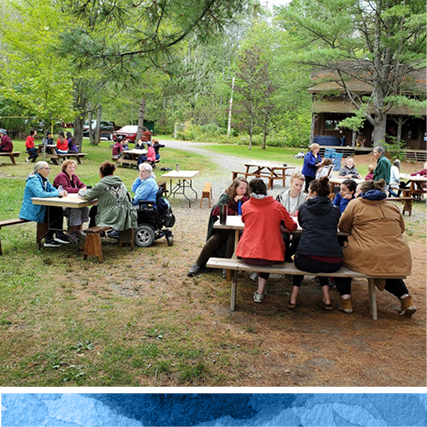 group of alumnae sitting outdoors at picnic tables